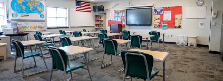 A bright classroom filled with wooden desks and chairs, ready for students to learn and explore new ideas together.