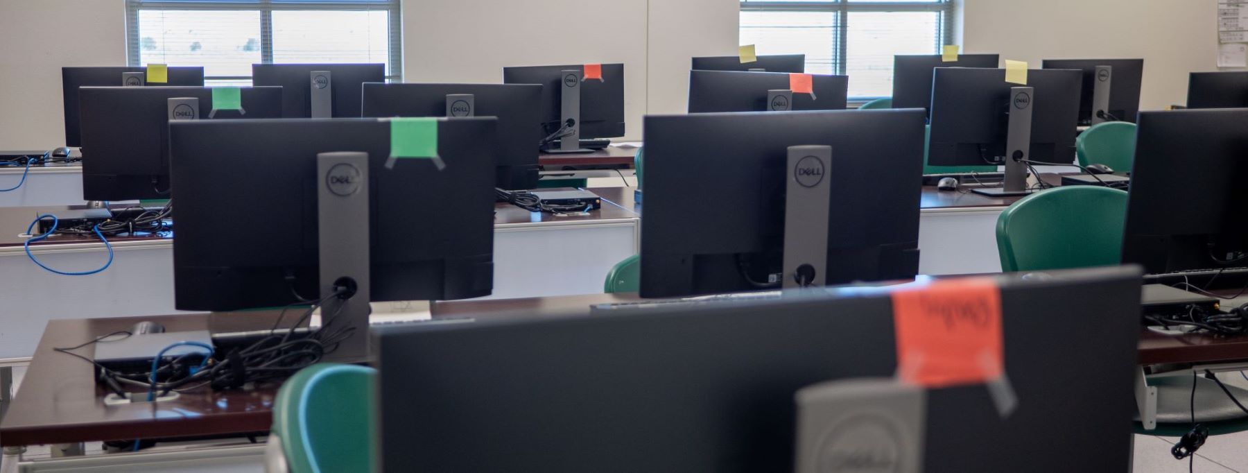 Interior of a classroom equipped with several computer monitors and green chairs for an engaging learning environment.