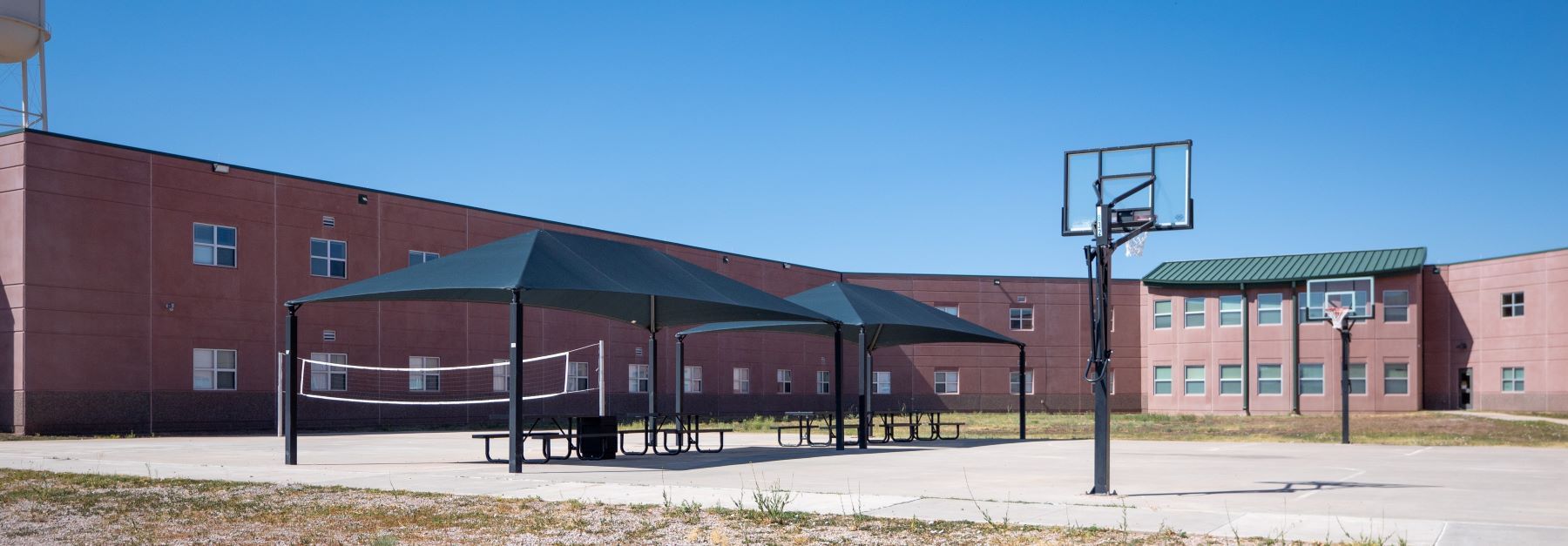 A basketball court in the school yard, with clear lines and a hoop visible on the court.