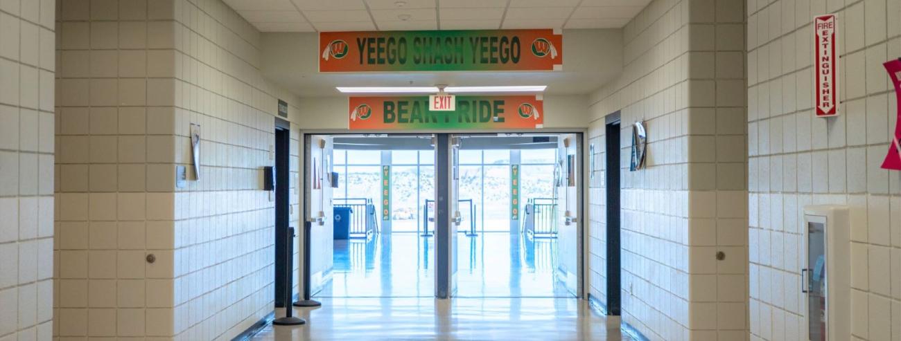 Looking down light-filled hallway to front doors of school.